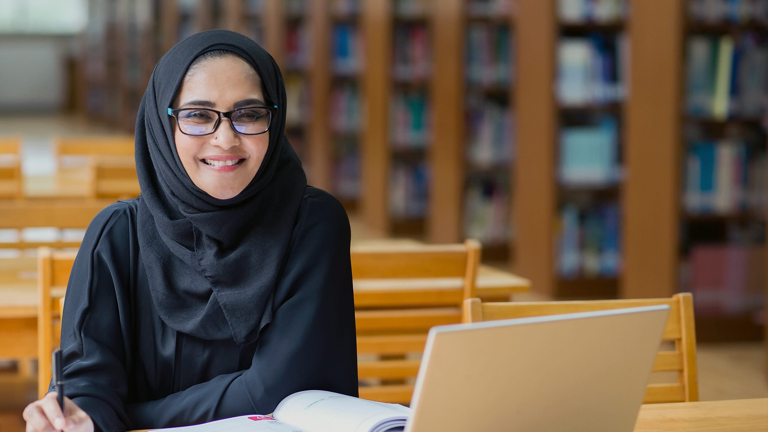 Woman with laptop working in the library.