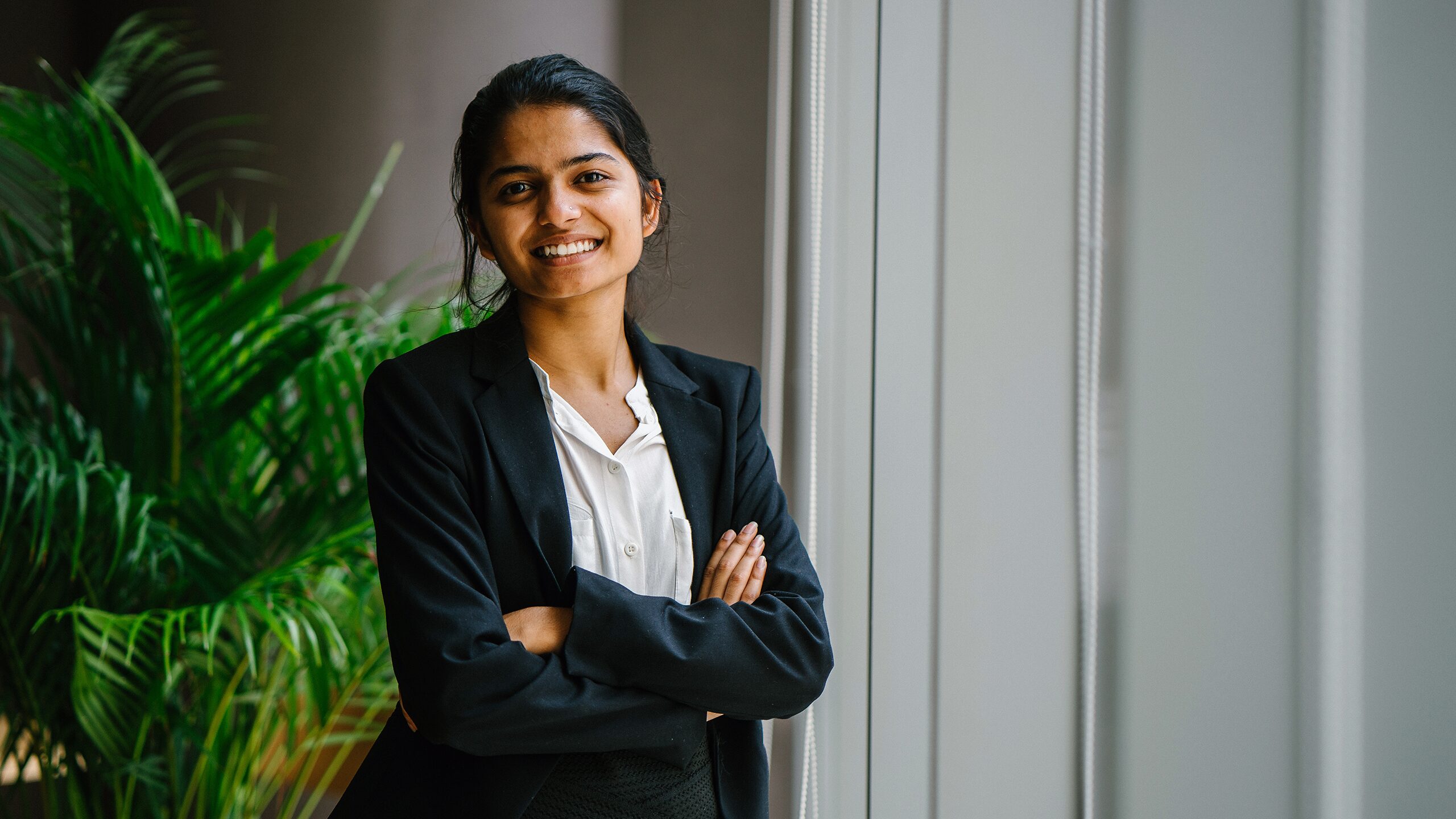Smiling woman in a suit standing with her arms crossed.